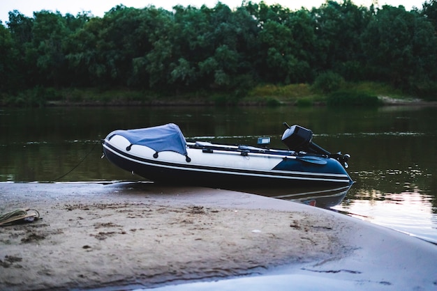 fisher inflatable motor boat on the sandy river bank at the dusk