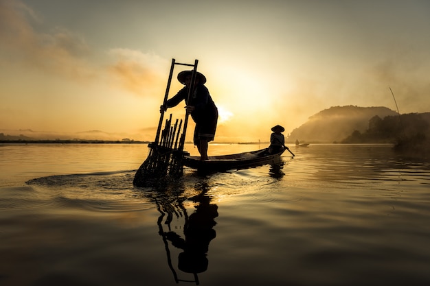 Fisherman in action when fishing in the lake , Thailand