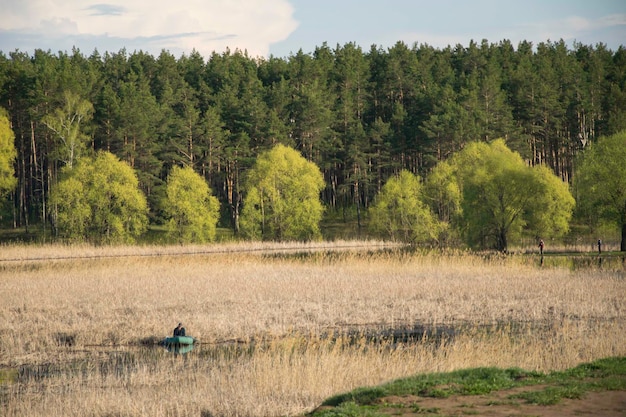 Fisherman on a boat in The bay of the Volga River with trees on the shore in early spring Ulyanovsk Russia