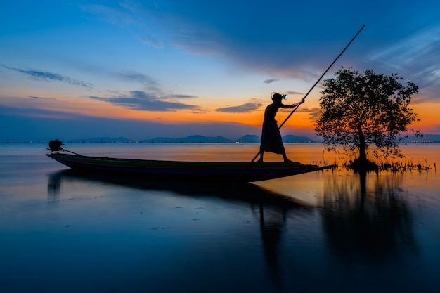 Pescatore sulla barca cattura pesci con sunrise