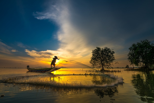 Fisherman on boat catching fish with sunrise 