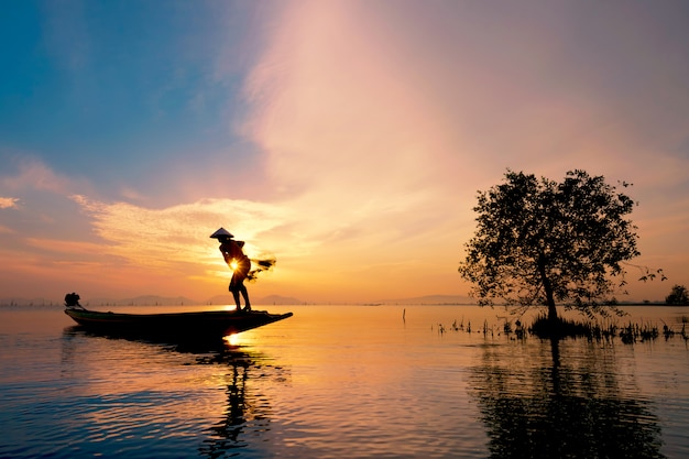 Fisherman on boat catching fish with sunrise 