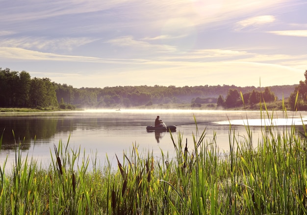 Photo fisherman on a boat on the lake a rubber boat on the surface of the water among the reeds