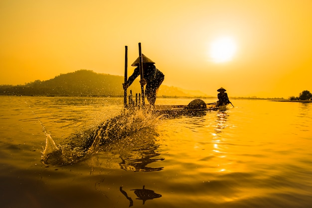 ボート川の夕日の漁師ボート夕日または日の出のアジア漁師竹魚トラップ