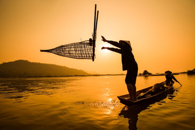 ボート川の夕日の漁師ボート夕日または日の出のアジア漁師竹魚トラップ