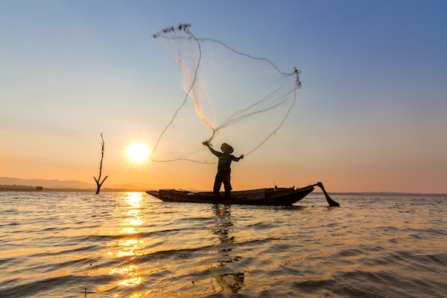 Fisherman cast net into the water in the morning