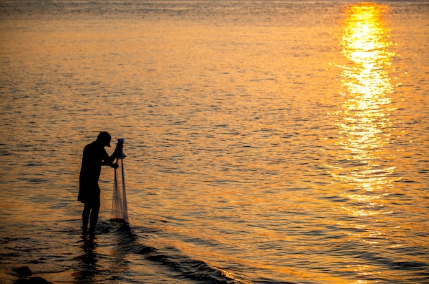 Il pescatore gettava una rete sul mare al mattino, all'alba