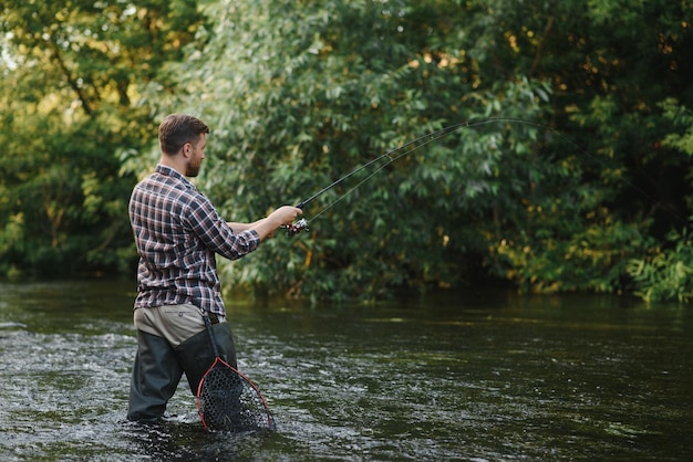 Fisherman catches a trout on the river in summer