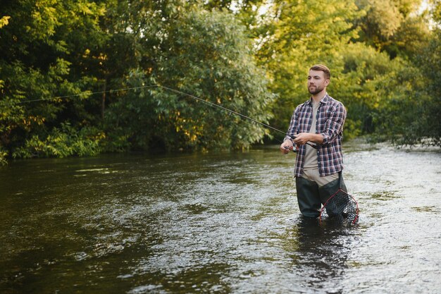 Fisherman catches a trout on the river in summer