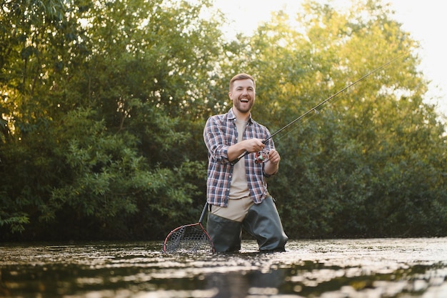 Fisherman catches a trout on the river in summer