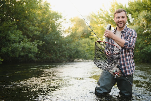 Fisherman catches a trout on the river in summer