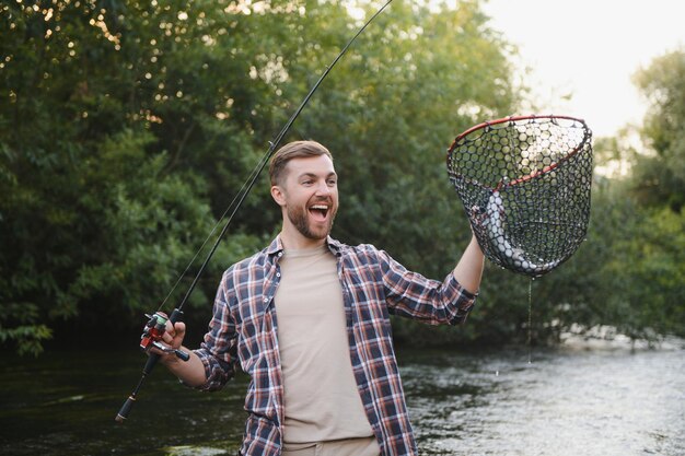 Fisherman catches a trout on the river in summer