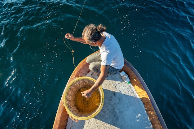 Fisherman catching fish in fishing net