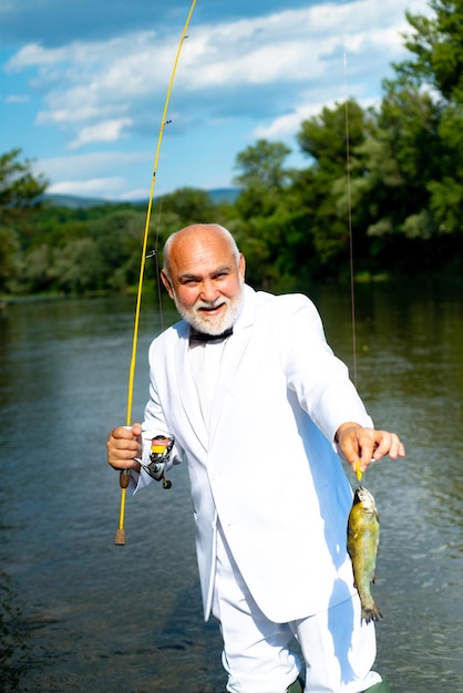 Fisherman caught a trout fish portrait of cheerful senior man\
fishing grandfather with catch fish ma