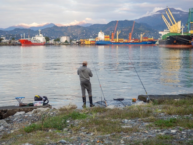 Fisherman on a concrete pier A fisherman in the port catches fish City fishing Atmosphere of an Asian port