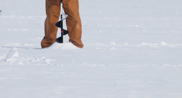 Fisherman eith an auger on the frozen lake Granby, Colorado.