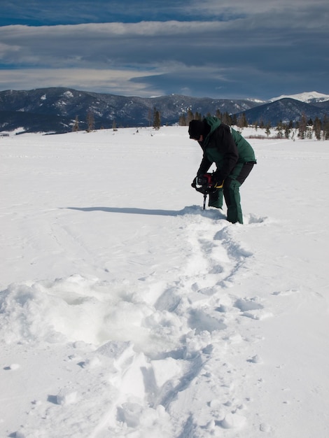 Fisherman eith an auger on the frozen lake Granby, Colorado.