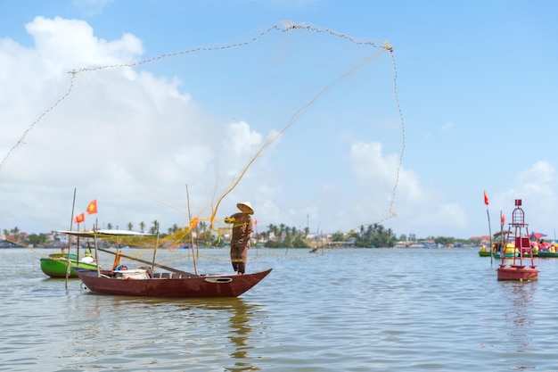 Рыбак ловит сеть на лодке в деревне Камтанх Ориентир и популярные среди туристов достопримечательности в Хойане Вьетнам и концепции путешествий по Юго-Восточной Азии