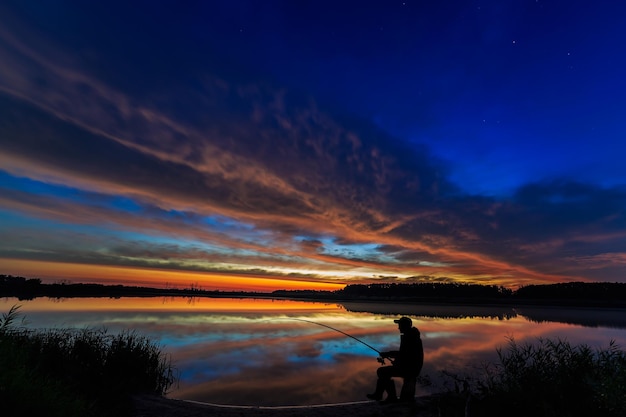 Fisherman fishing rod at dawn on the lake.