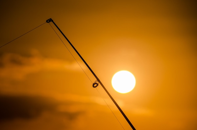 Foto pescatore canna da pesca silhouette al tramonto arancione