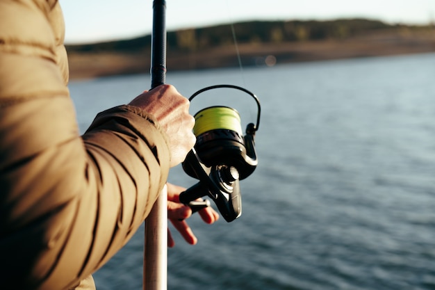 Fisherman hands holding fishing rod close up