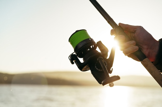 Mani del pescatore che tengono la canna da pesca da vicino