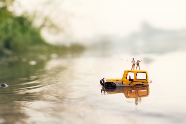 Fisherman holding a fishing rod for catching fish (miniature, toy model )