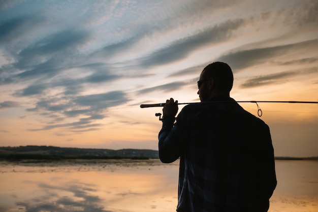 Fisherman holding the spinning rod by the lake