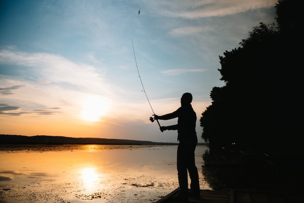 Fisherman holding the spinning rod by the lake
