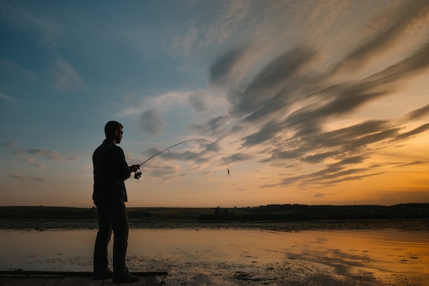 Fisherman holding the spinning rod by the lake