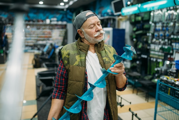 Fisherman holds a drill for winter fishing in shop