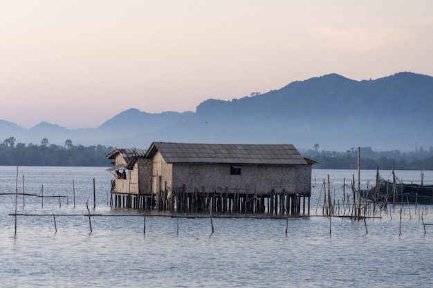 Foto capanna del pescatore in mezzo al lago con la bella luce del mattino e le montagne sullo sfondo.