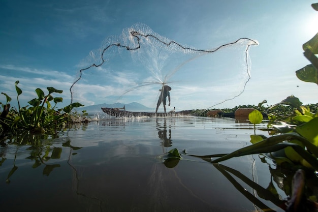 A fisherman is casting a net in the water.