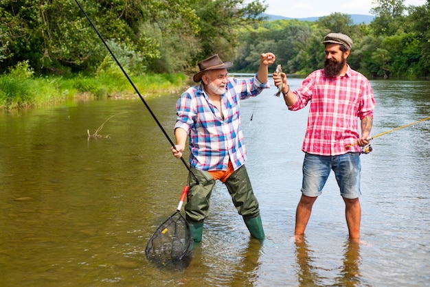 Fisherman men friends and trophy trout Father and son fishing Generations men fishing in river Happy excited man friends