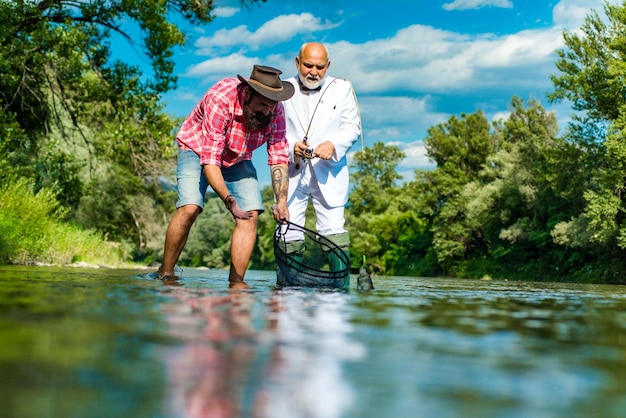 Fisherman men friends and trophy trout father and son fishing generations men fishing in river