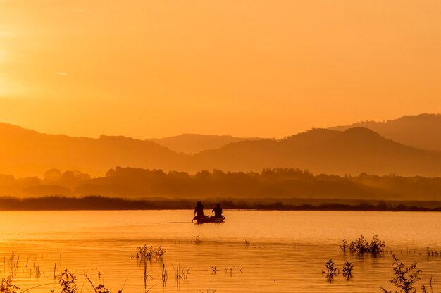 Fisherman rowing boat on the lake in the morning 