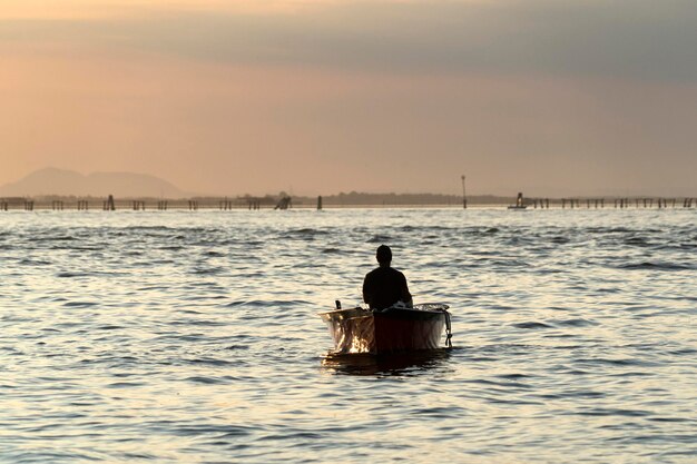 Fisherman silhouette at Sunset in Venice lagoon chioggia harbor from a boat