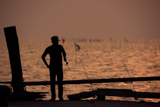 La silhouette del pescatore con il cielo al tramonto