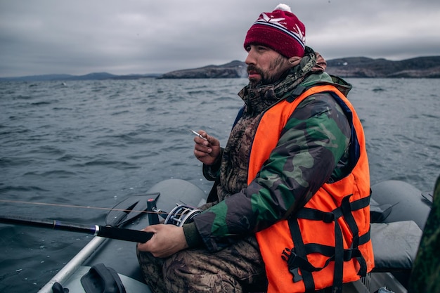 A fisherman sits in a boat and smokes