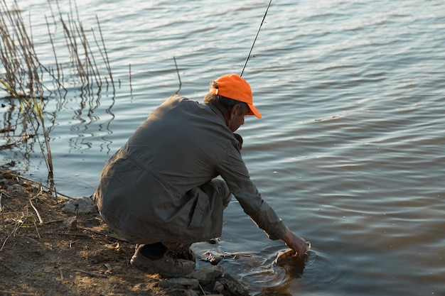 Рыбак стоит на берегу реки и пытается поймать рыбу