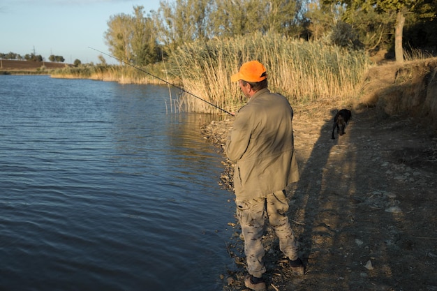 川沿いに立って魚を捕まえようとしている漁師スポーツレクリエーションライフスタイル