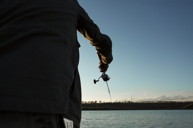 Fisherman standing on the riverside and trying to catch a fish. Sport, recreation, lifestyle.