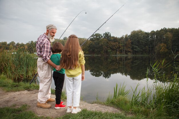 fisherman teaching his grandkids fishing on the lake