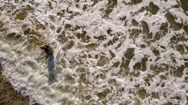 Fisherman Wades in Ocean Surf Hoping to Catch Fish