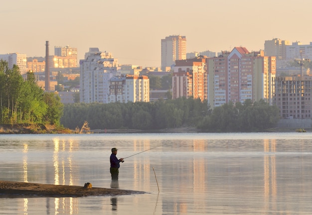 Фото Рыбак с удочкой по колено в воде на рассвете утром на реке обь