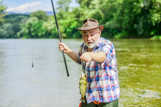 Fisherman with fishing rod Activity and hobby Fishing freshwater lake pond river It is not sport it is obsession Senior bearded man catching fish Mature man fishing Retired bearded fisherman
