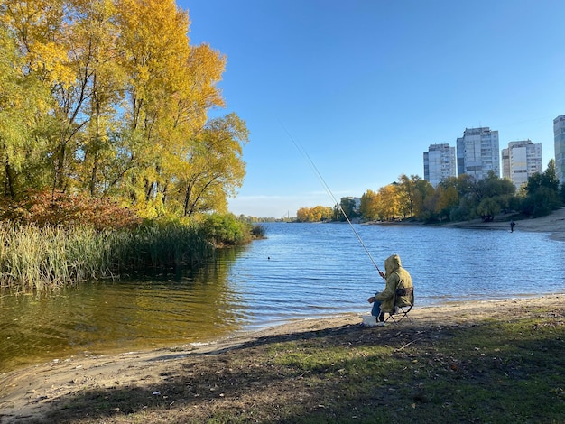 Foto un pescatore con una canna da pesca sullo sfondo di un paesaggio autunnale sul fiume