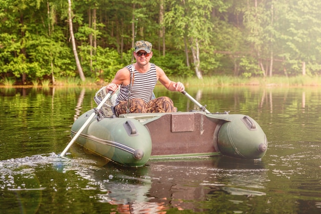 Fisherman with fishing rods is fishing in a rubber boat on lake or river