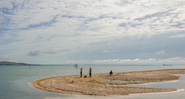 Fishermen are standing on a sandbar near the sea.