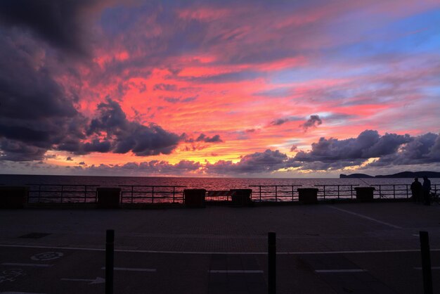 Fishermen and bike lane under a colorful sky in Alghero at sunset Italy